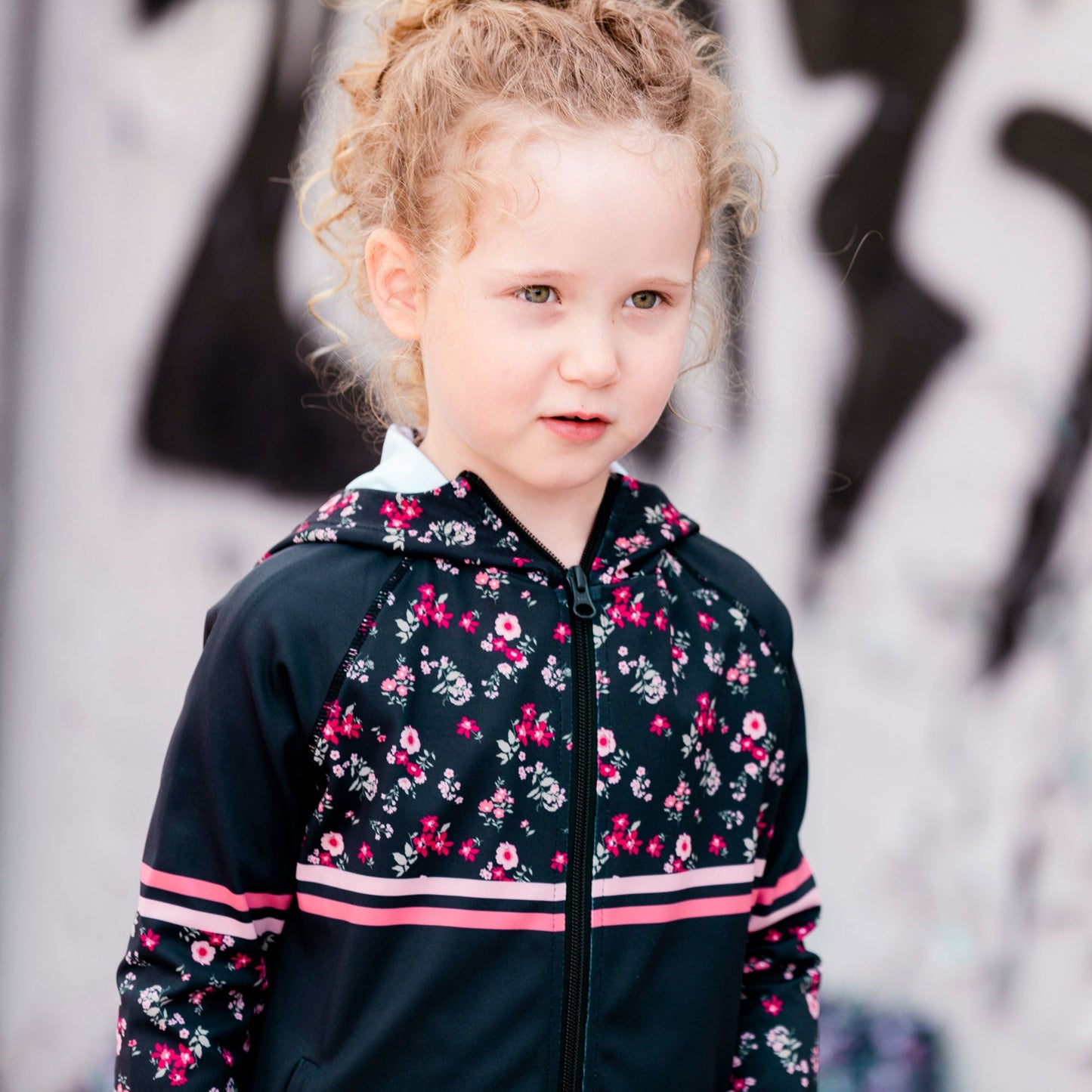 With floral print panels, this zip front jacket is equal parts sporty and sweet. Our Hooded Athletic Vest With Printed Flowers is made from stretch poly/elastane.  Features half-printed raglan sleeves, a printed hood, horizontal stripes across the chest and sleeves, and a logo print on the left chest.