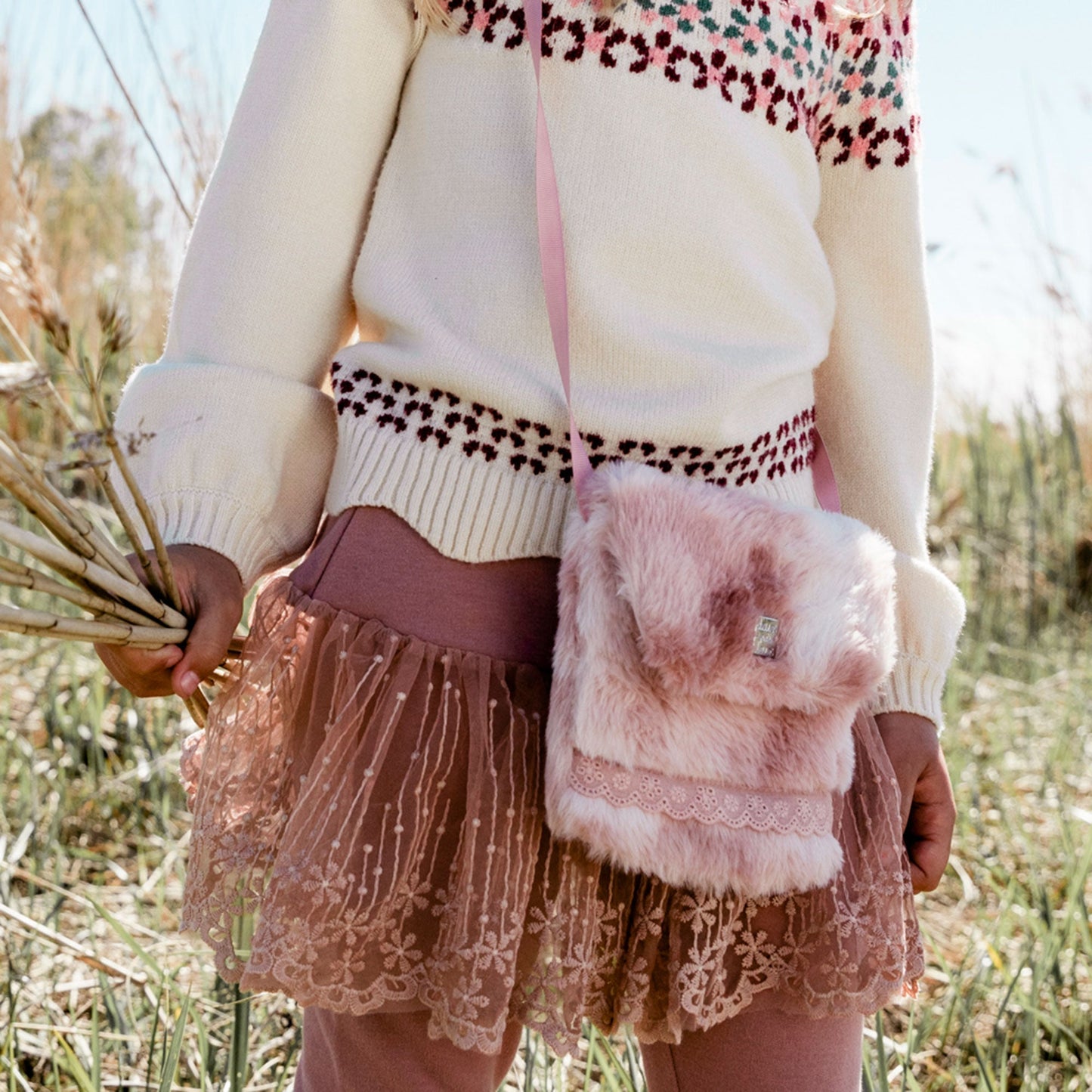 She can carry her essentials in style inside our Silver Pink Fake Fur Bag. In a chic crossbody silhouette, this petite bag is made from poly faux fur.  Features a flap front silhouette with a slim strap for easy carrying and eyelet lace trim for added texture.