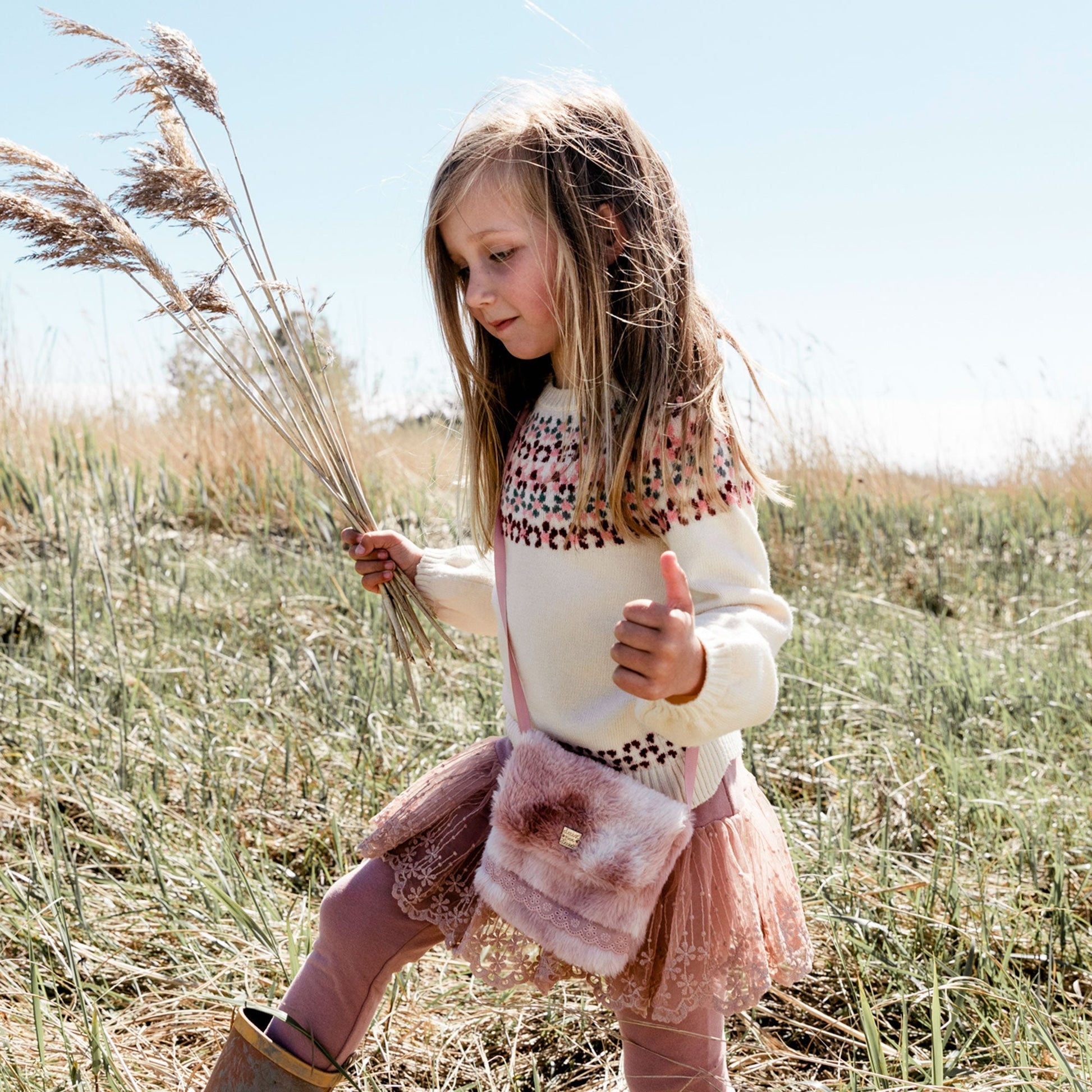 She can carry her essentials in style inside our Silver Pink Fake Fur Bag. In a chic crossbody silhouette, this petite bag is made from poly faux fur.  Features a flap front silhouette with a slim strap for easy carrying and eyelet lace trim for added texture.