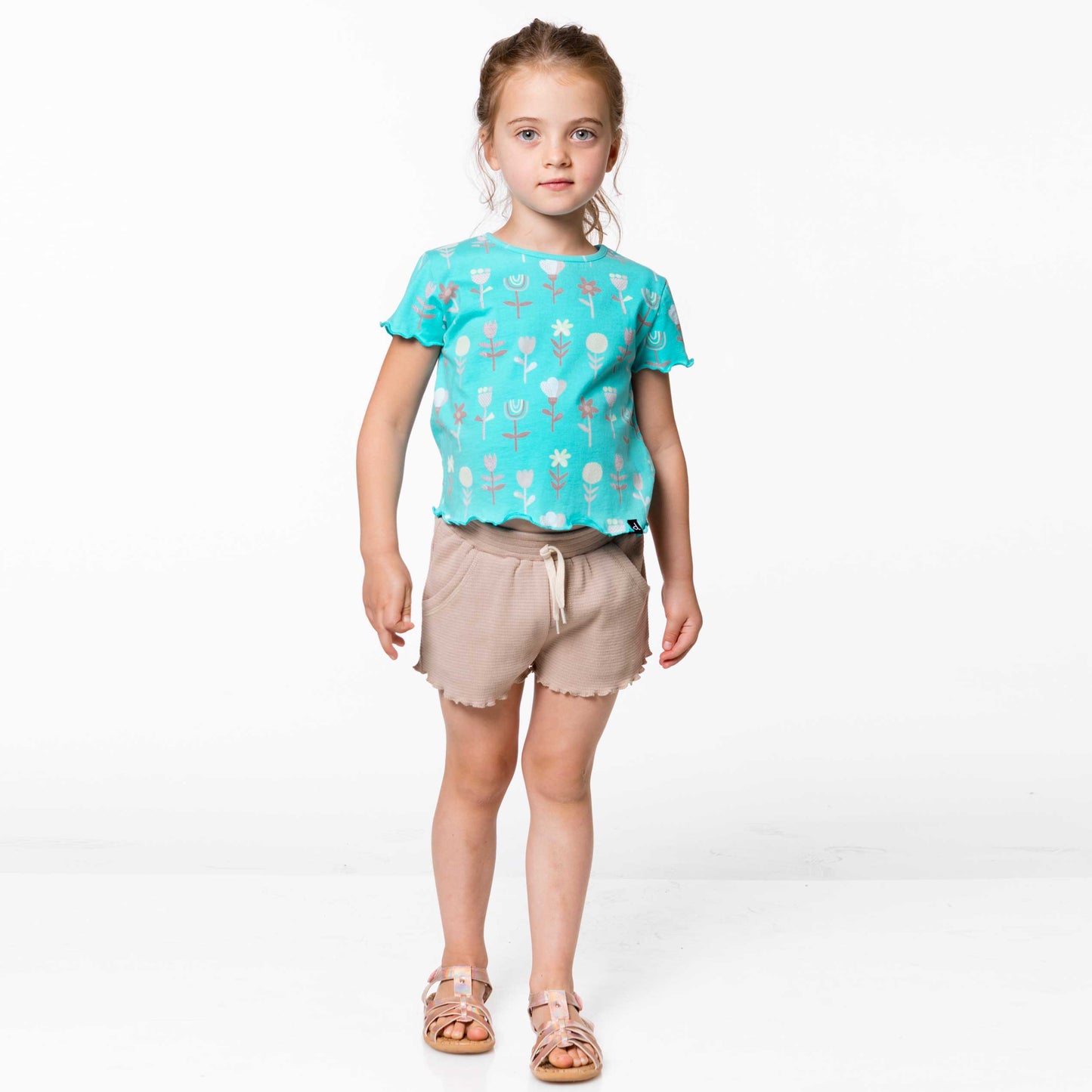 An allover flower print makes this comfy tee shirt perfect for any spring or summer day. Our Turquoise Flowers Printed T-Shirt is made from 100% cotton.  Features short sleeves, a round neckline, and a keyhole with a button closure at the back of the neck. Lettuce edging at the sleeves and hem adds an ultra-girly touch.